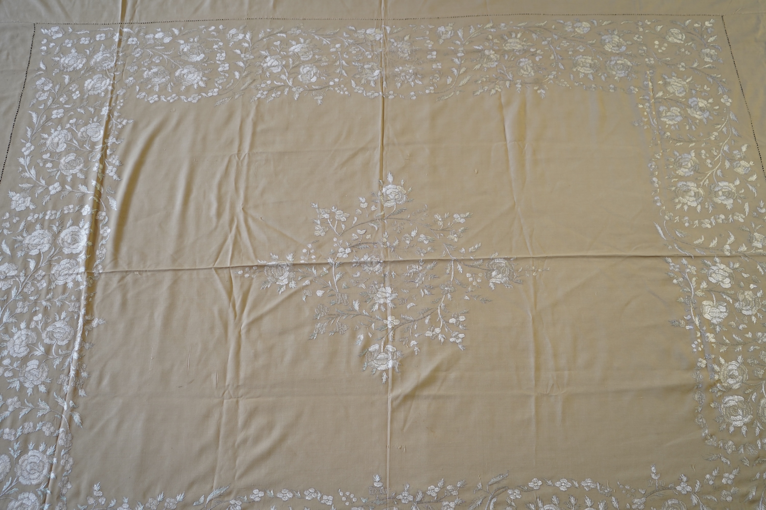 A 1920’s heavy shantung silk hand embroidered table cover. Worked with decorative rows of button hole stitch. Embroidered with white, green and blue silk flowers. 240cm x 204cm. Condition - some fine holes near corners,